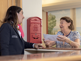 Recepción de DomusVi con un residente recibiendo correo en la recepción de la residencia.